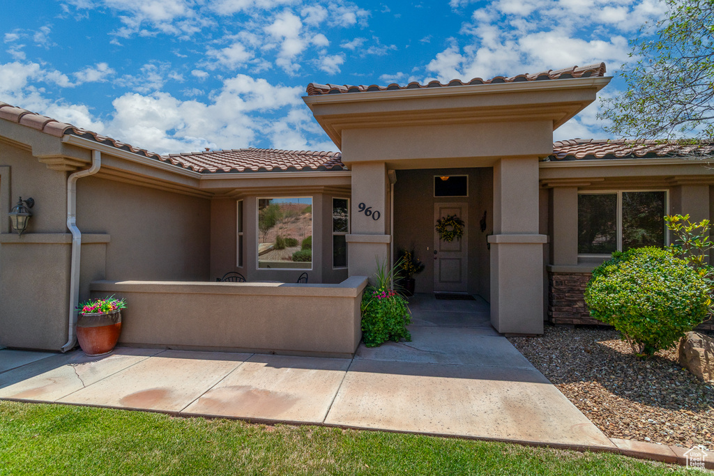 View of exterior entry featuring a tiled roof and stucco siding