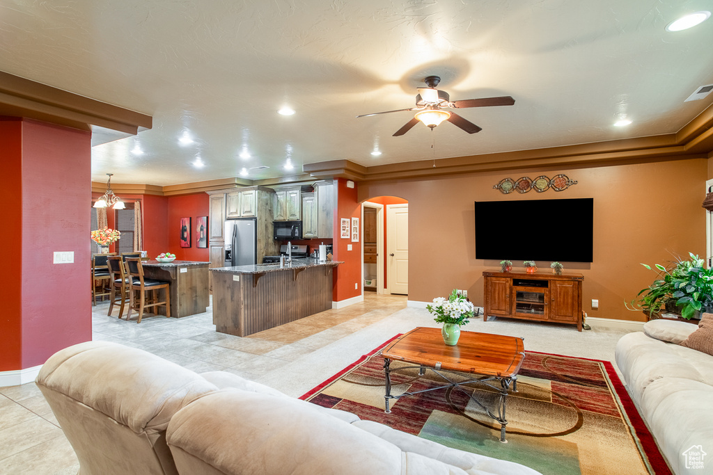 Living area with arched walkways, ceiling fan, light tile patterned flooring, recessed lighting, and a chandelier