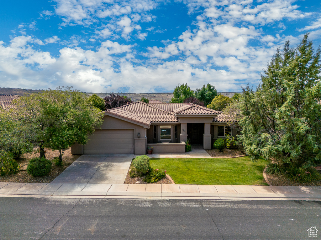 Mediterranean / spanish-style house with a tile roof, a garage, stucco siding, concrete driveway, and a front lawn
