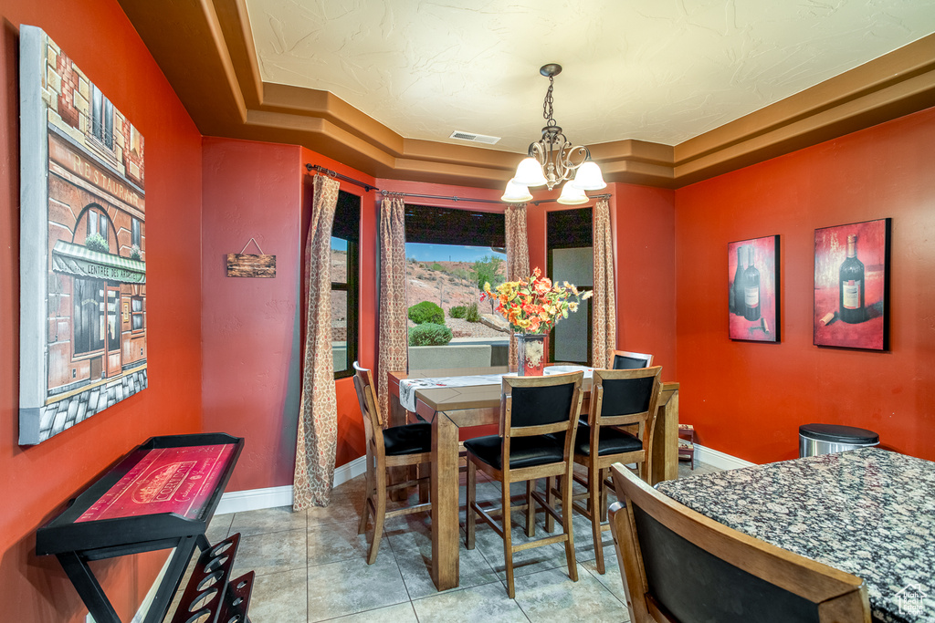 Tiled dining room featuring a chandelier and a tray ceiling