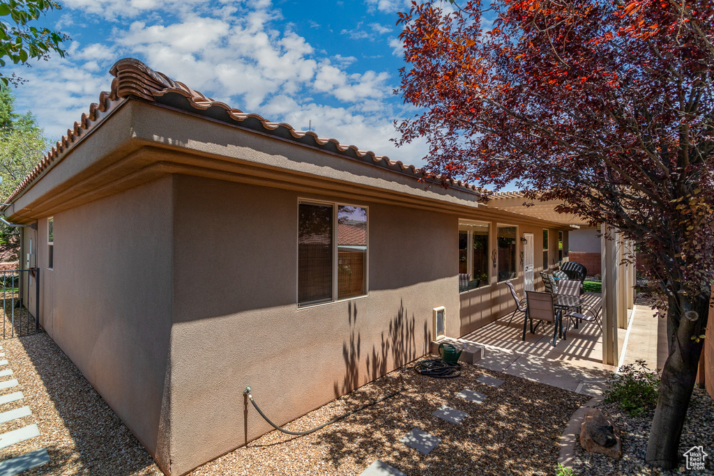View of side of property with a patio, stucco siding, and a tiled roof