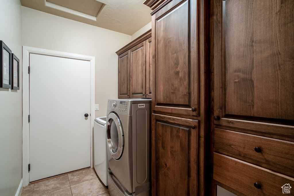 Laundry room with cabinet space, attic access, independent washer and dryer, and light tile patterned floors