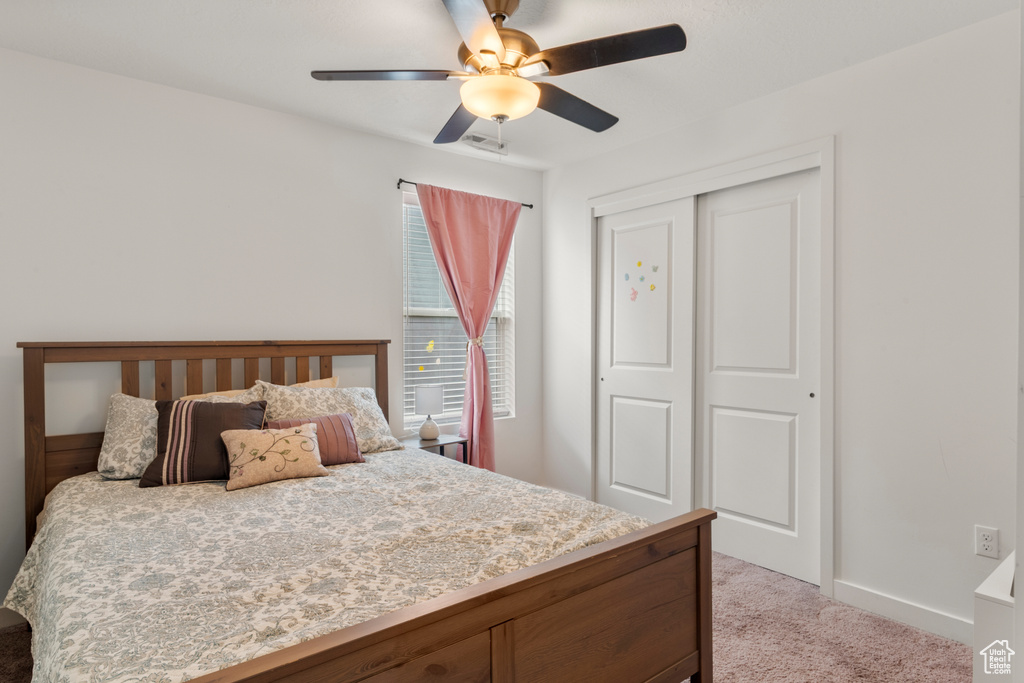 Carpeted bedroom featuring a closet and a ceiling fan