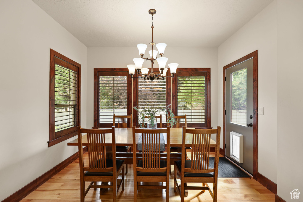Dining space with light wood-type flooring, a chandelier, and plenty of natural light