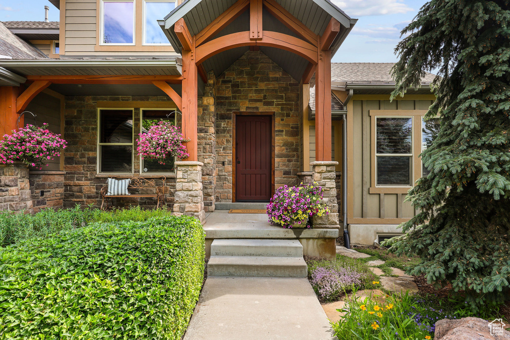 Entrance to property with stone siding and roof with shingles