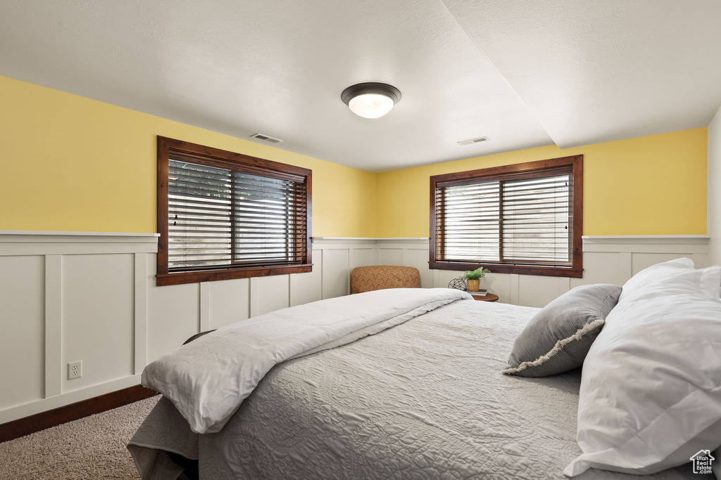 Bedroom with wainscoting and a decorative wall