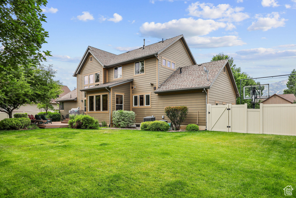 Rear view of property featuring a gate, a wooden deck, and a shingled roof