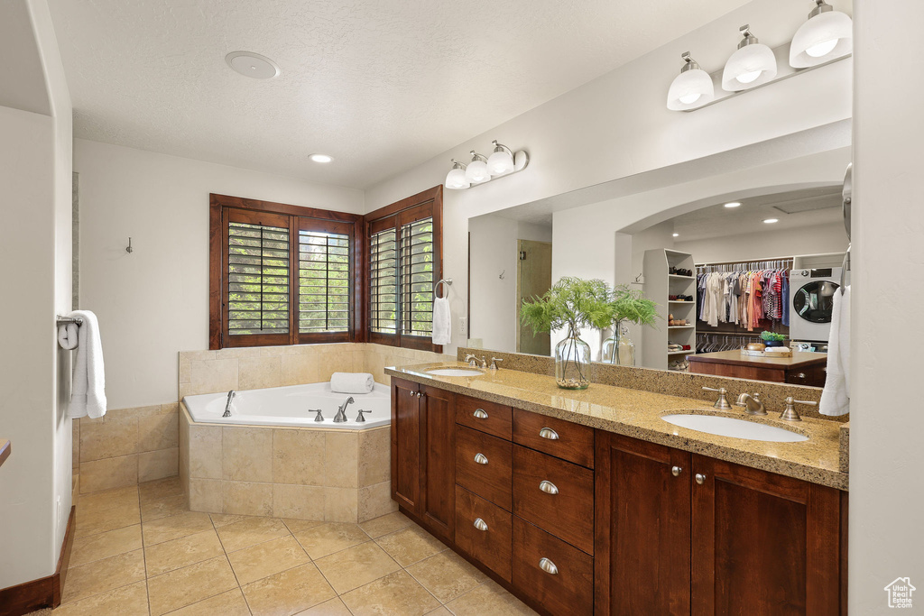 Bathroom featuring a garden tub, tile patterned flooring, double vanity, and a spacious closet