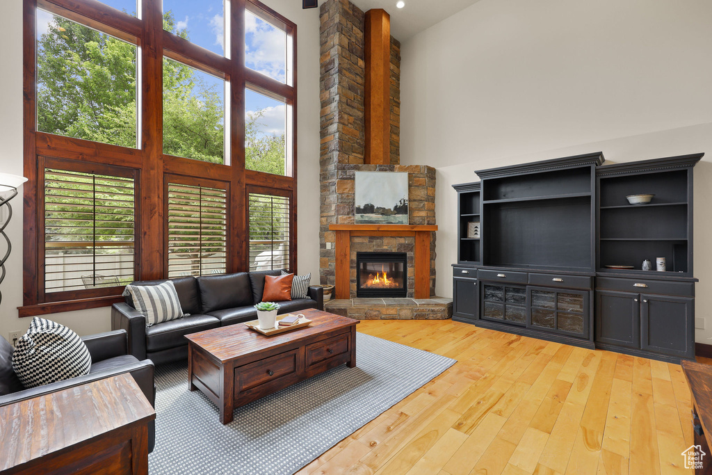 Living room with a towering ceiling, wood finished floors, and a stone fireplace