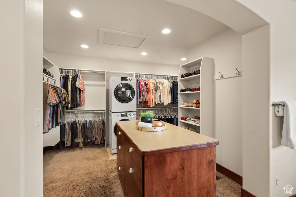 Spacious closet featuring attic access, estacked washer and dryer, and light colored carpet