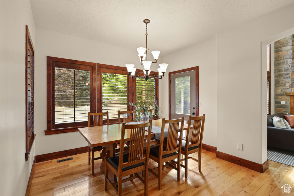 Dining room featuring light wood finished floors, healthy amount of natural light, and a chandelier