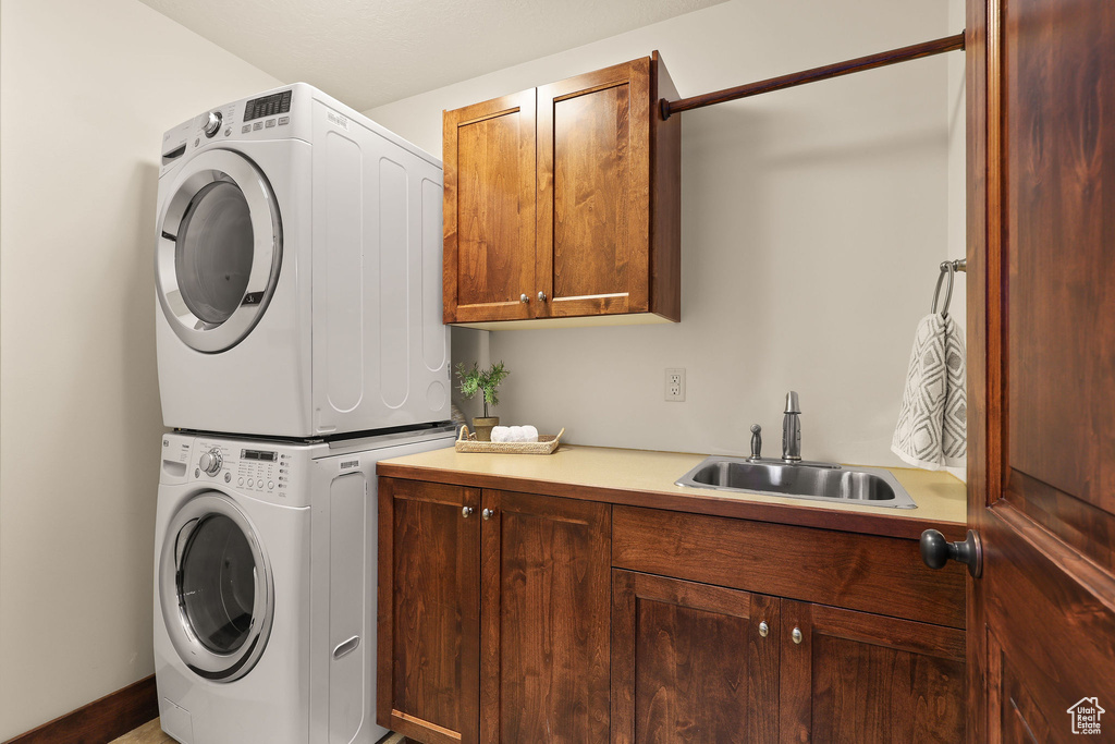 Washroom featuring stacked washing machine and dryer and cabinet space
