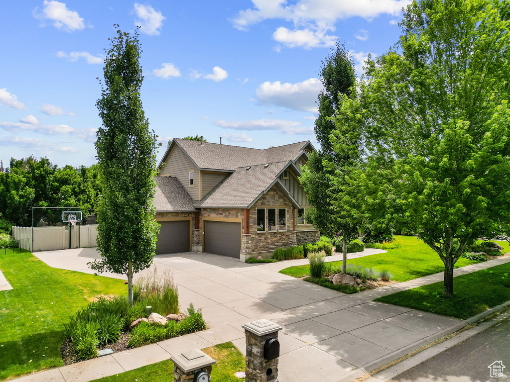 View of front facade featuring stone siding, an attached garage, concrete driveway, and roof with shingles