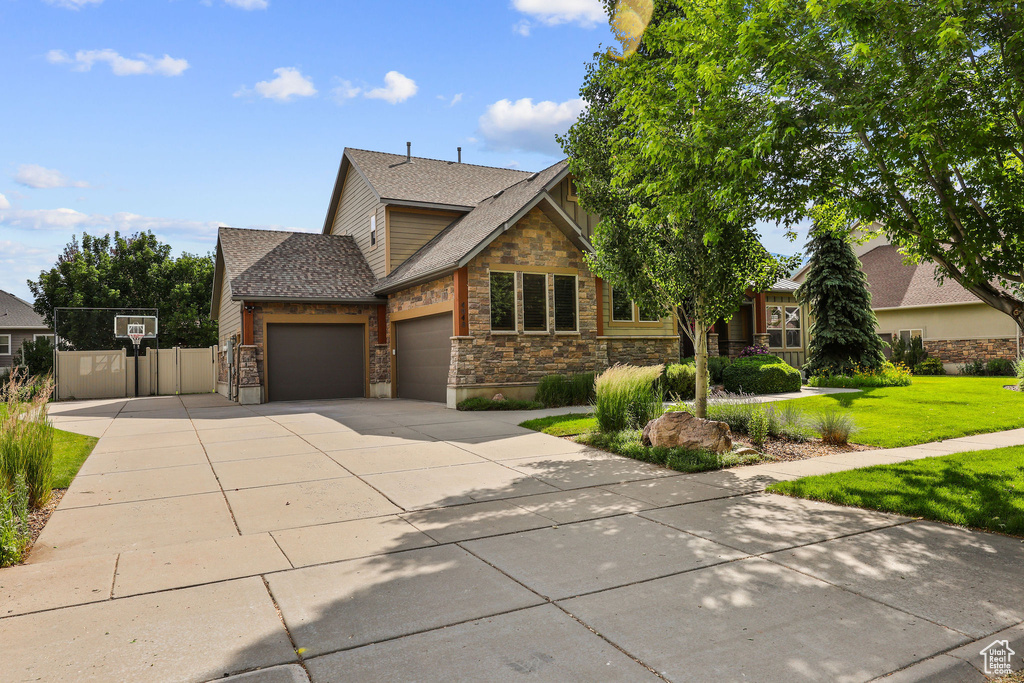 View of front of house featuring a garage, stone siding, a shingled roof, and concrete driveway