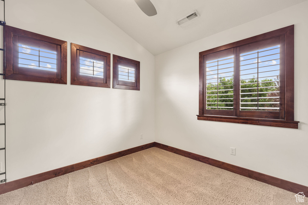 Carpeted spare room featuring lofted ceiling and ceiling fan