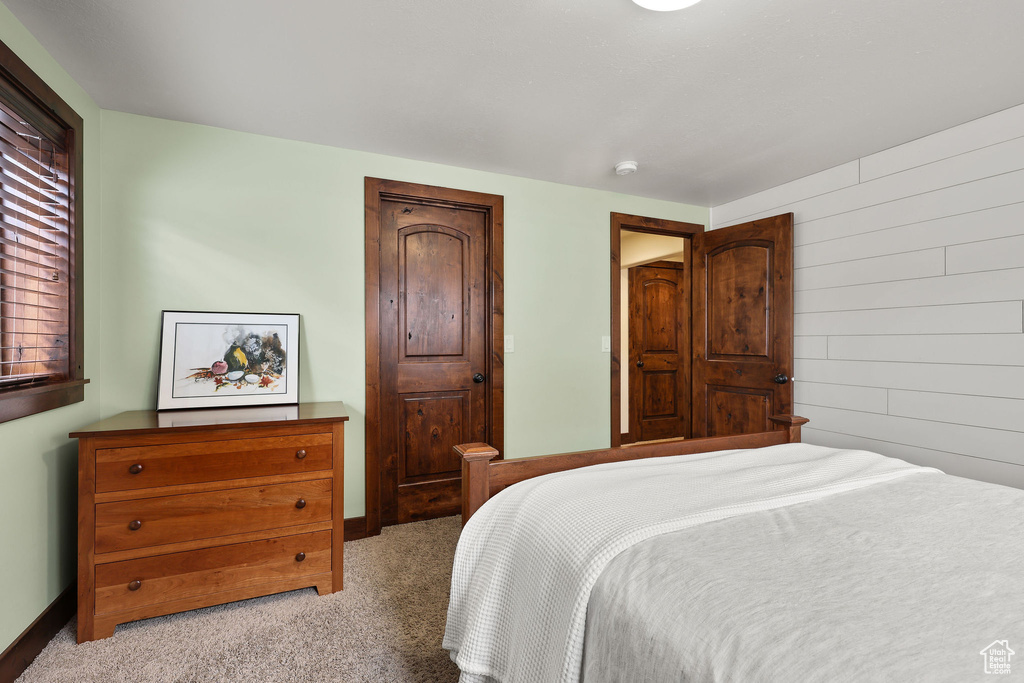 Bedroom with carpet floors and wooden walls