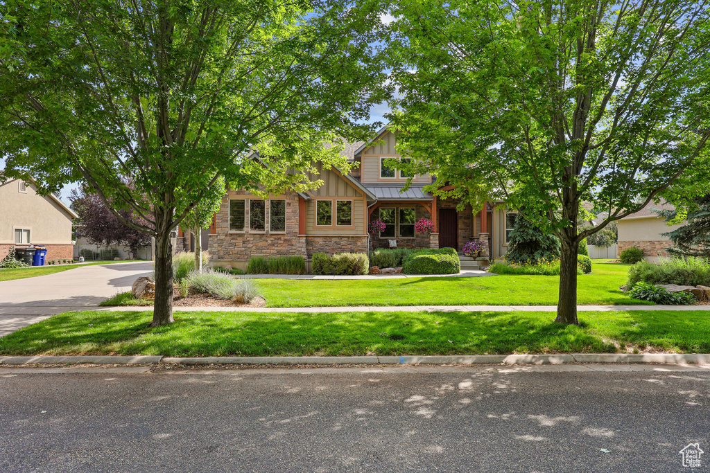 View of front of property featuring stone siding, board and batten siding, and a front yard