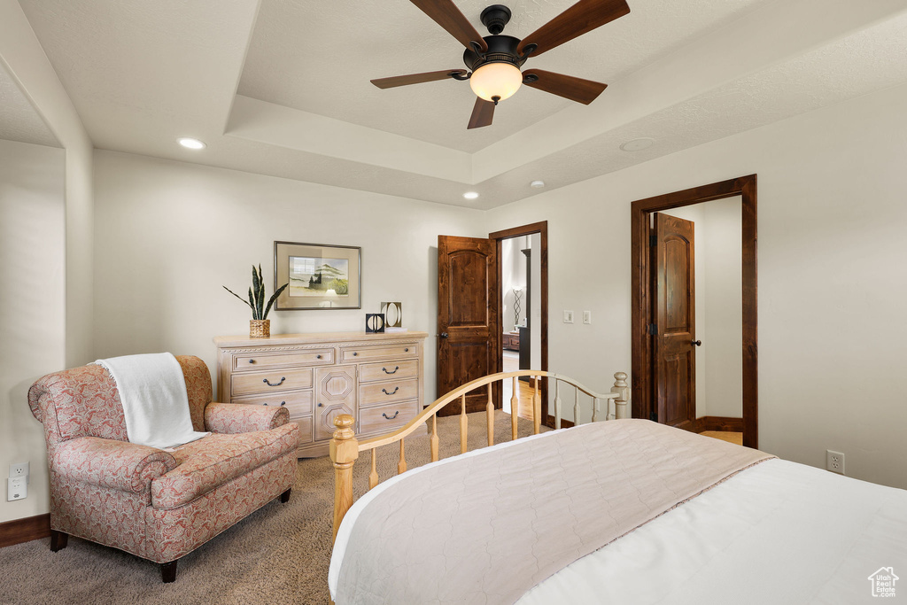 Carpeted bedroom with recessed lighting, ceiling fan, and a raised ceiling
