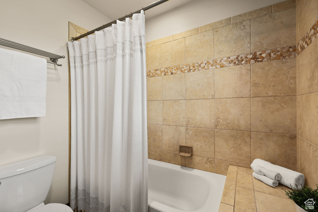 Full bathroom featuring toilet and shower / bath combo with shower curtain