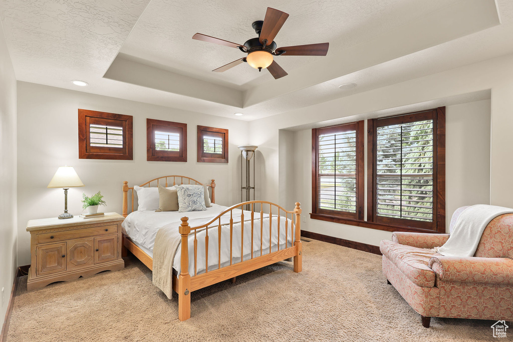 Bedroom featuring light colored carpet, a raised ceiling, a ceiling fan, and recessed lighting