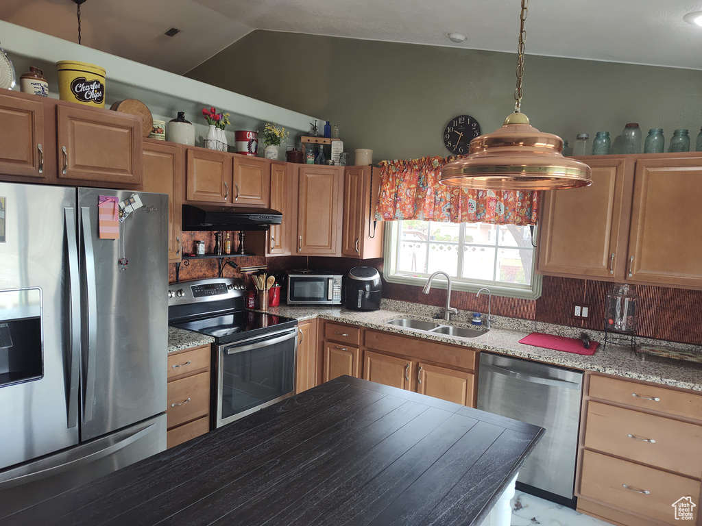 Kitchen featuring stainless steel appliances, under cabinet range hood, backsplash, vaulted ceiling, and decorative light fixtures