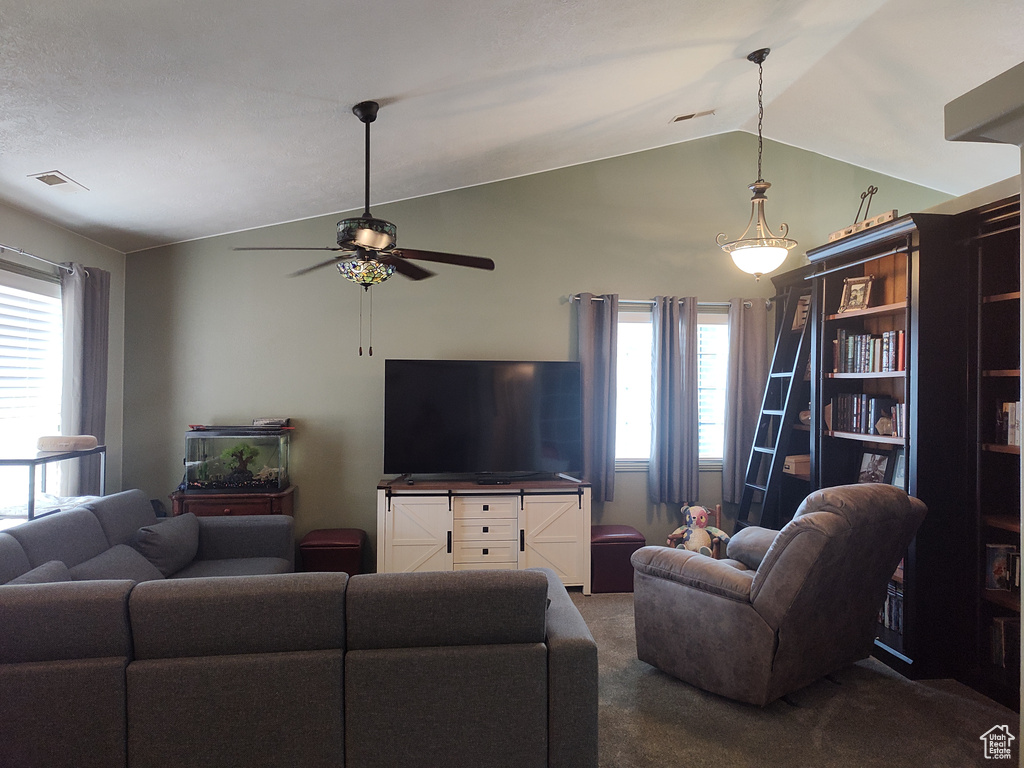 Living room with lofted ceiling, dark colored carpet, and ceiling fan