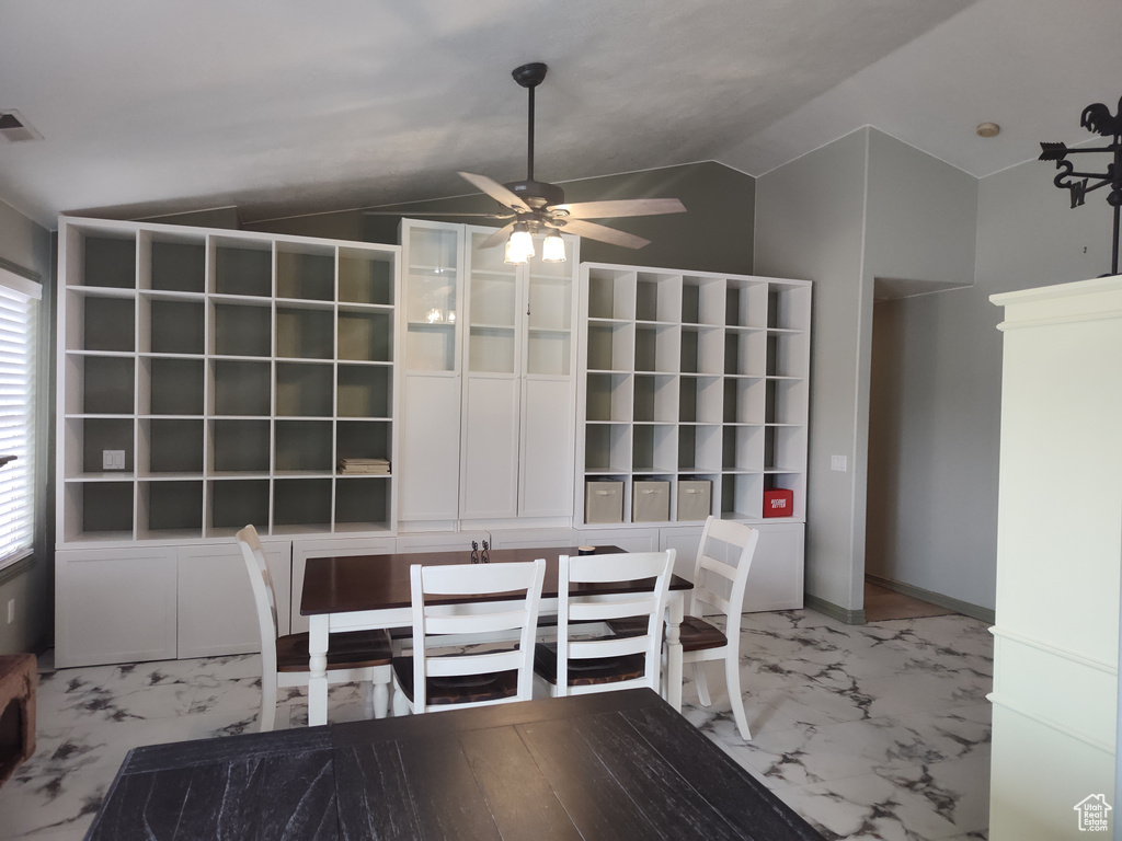 Unfurnished dining area featuring vaulted ceiling, light marble finish flooring, and a ceiling fan