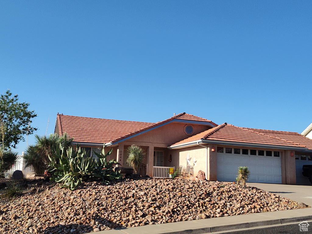 Ranch-style house with a tiled roof, a garage, driveway, and stucco siding