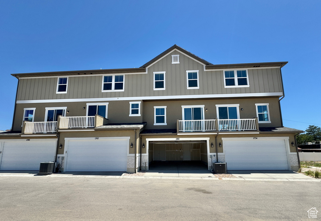 View of front of home with an attached garage, stucco siding, and a balcony