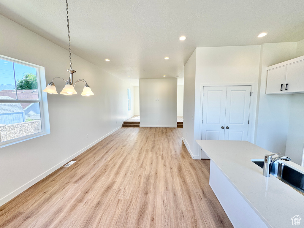 Unfurnished dining area featuring a chandelier, light wood-style floors, and recessed lighting