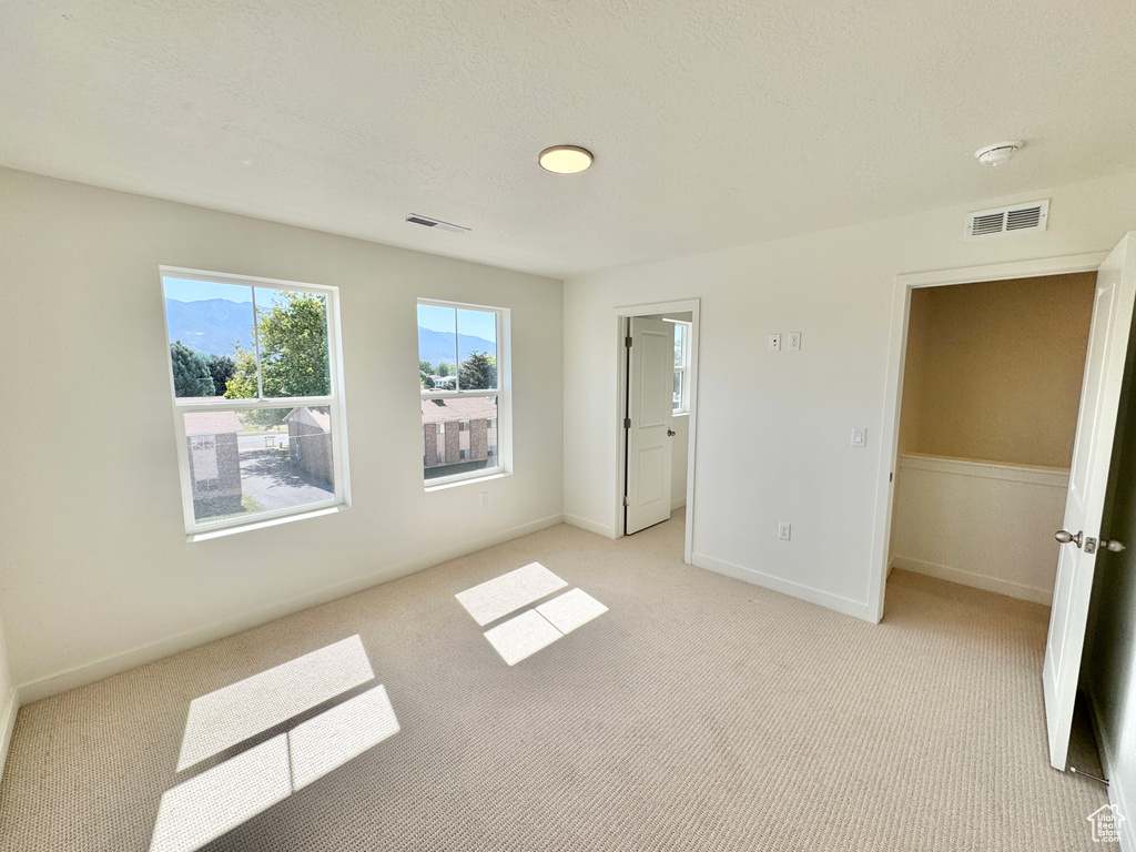 Unfurnished bedroom with light colored carpet and baseboards
