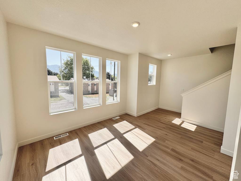 Unfurnished living room with plenty of natural light, wood finished floors, recessed lighting, and stairs