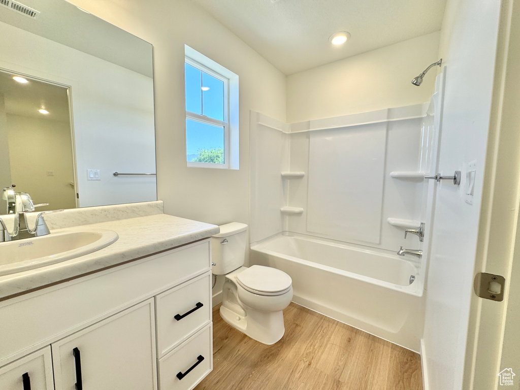 Bathroom featuring wood finished floors, vanity, bathtub / shower combination, and recessed lighting