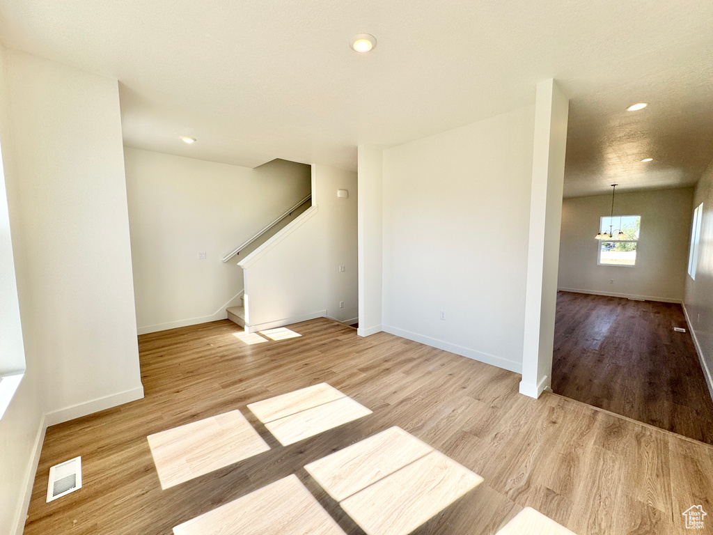 Unfurnished living room featuring wood finished floors, recessed lighting, stairs, and a chandelier