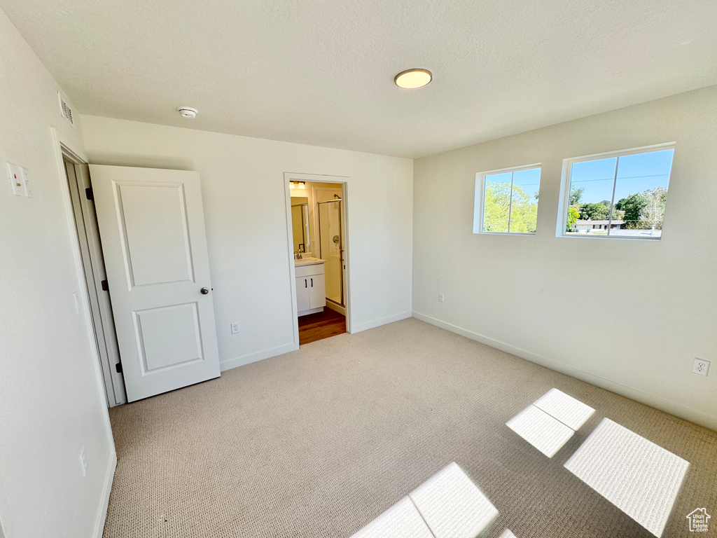 Unfurnished bedroom featuring carpet and connected bathroom