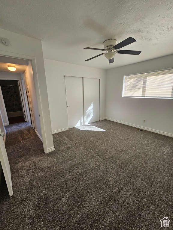 Unfurnished bedroom with carpet floors, a closet, a textured ceiling, and ceiling fan