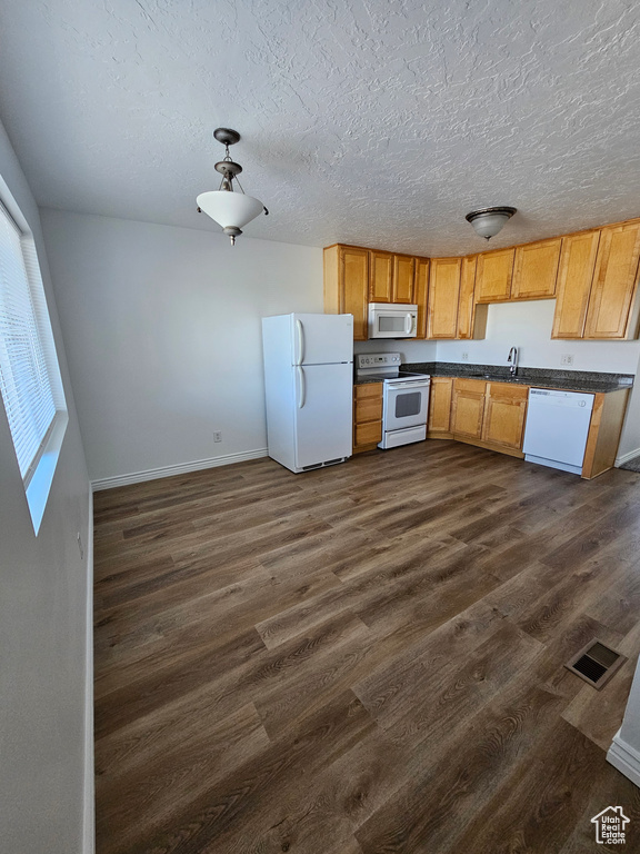 Kitchen featuring white appliances, dark countertops, dark wood-style floors, and a textured ceiling