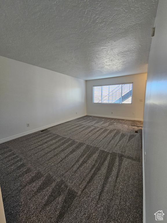 Carpeted empty room featuring baseboards and a textured ceiling