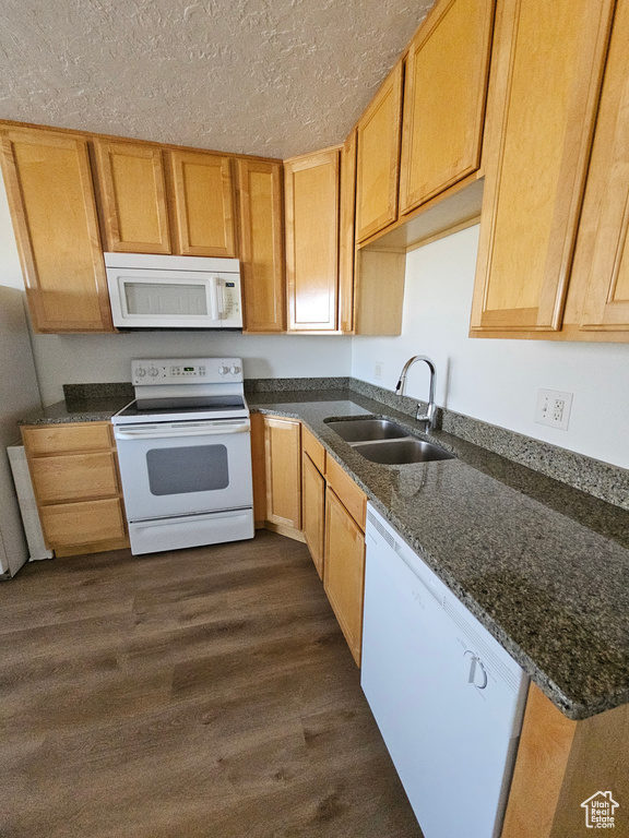 Kitchen featuring white appliances, dark wood-style flooring, a textured ceiling, and dark stone countertops