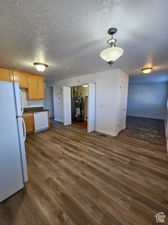 Kitchen featuring white appliances, water heater, dark wood-style floors, dark countertops, and a textured ceiling