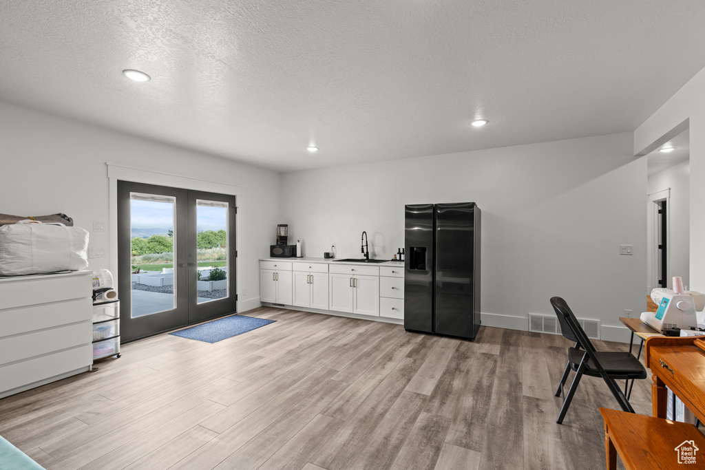 Kitchen featuring black fridge, french doors, light wood-style flooring, white cabinets, and recessed lighting