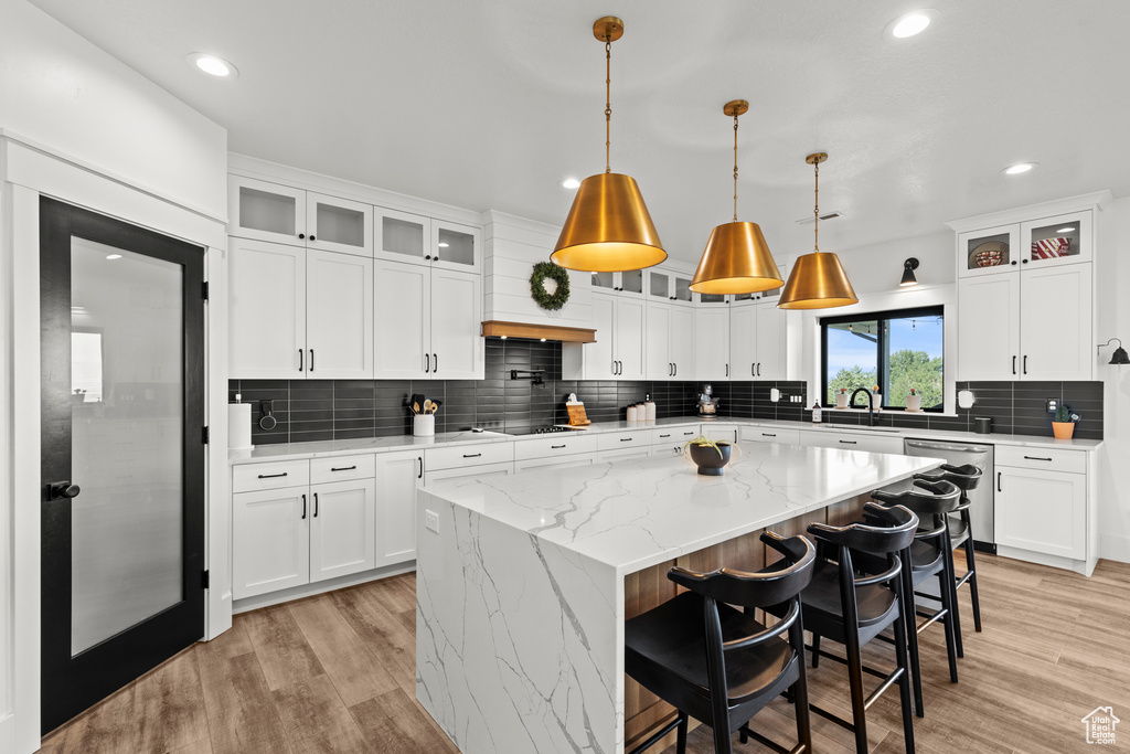 Kitchen featuring stainless steel dishwasher, light wood-type flooring, decorative backsplash, recessed lighting, and black electric cooktop