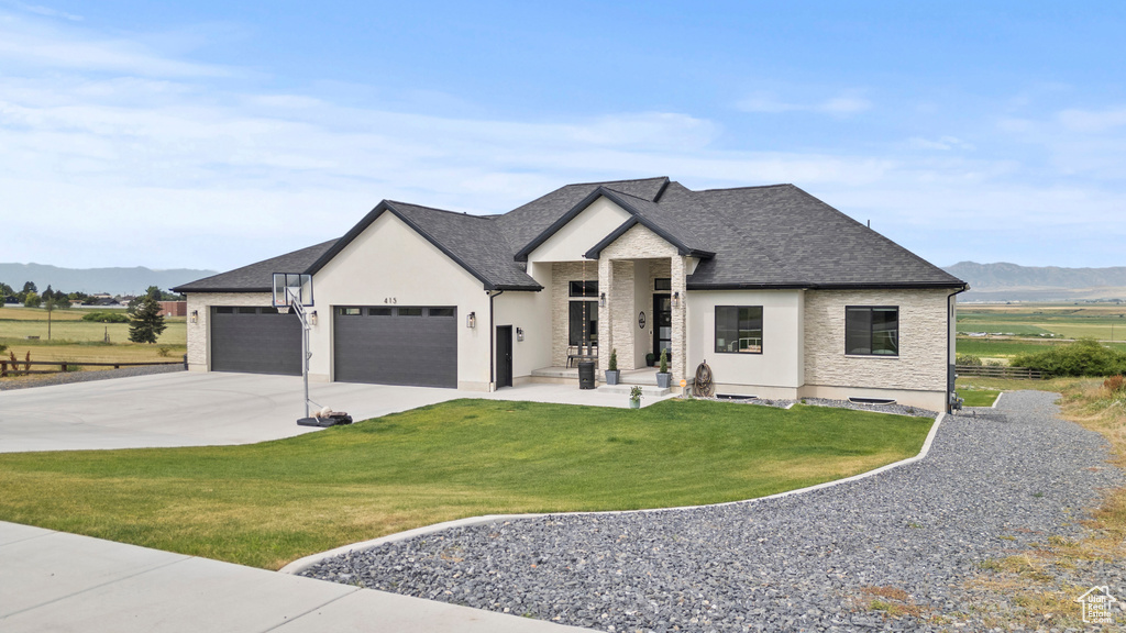 French country home with a mountain view, an attached garage, a front lawn, and concrete driveway