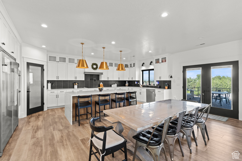 Dining room with french doors, light wood finished floors, and recessed lighting