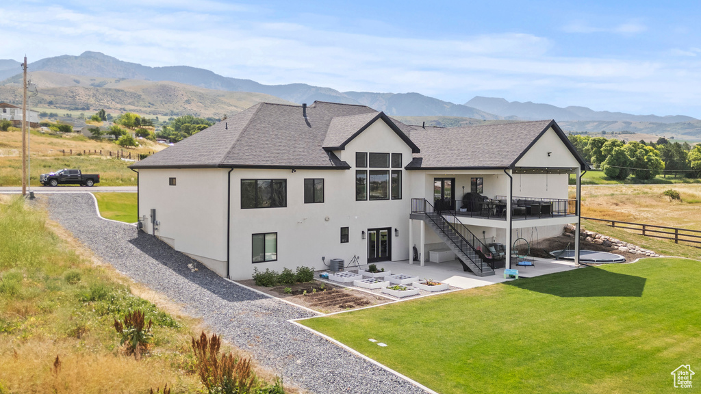 Back of property with a patio, stairs, a deck with mountain view, a shingled roof, and stucco siding