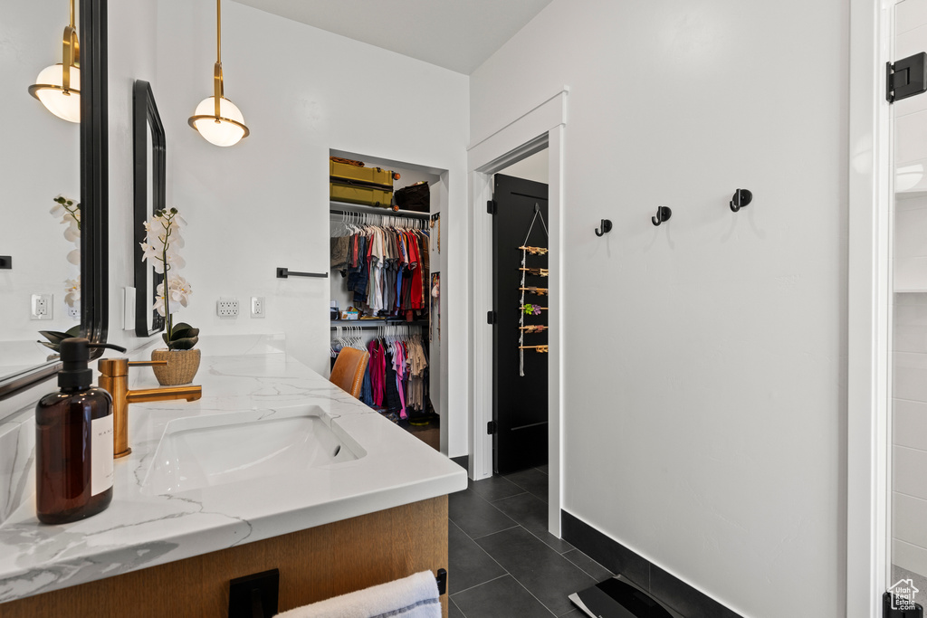 Bathroom with double vanity, a spacious closet, and tile patterned flooring