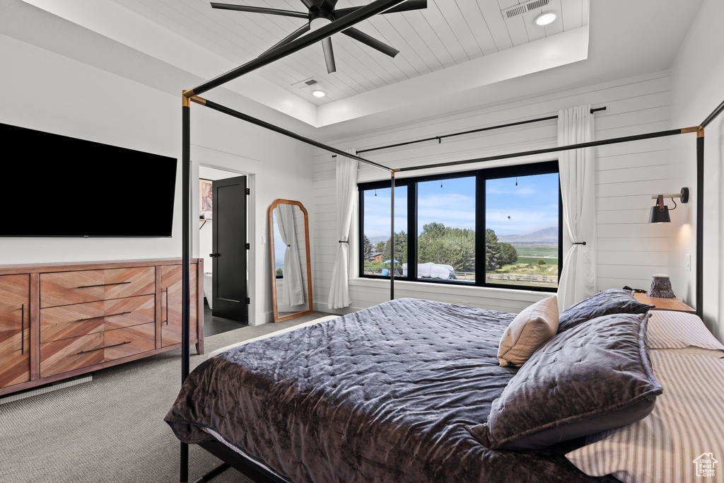 Bedroom featuring carpet, a tray ceiling, and ceiling fan