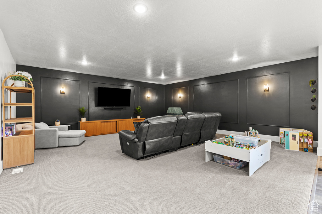 Carpeted living area with a decorative wall and recessed lighting