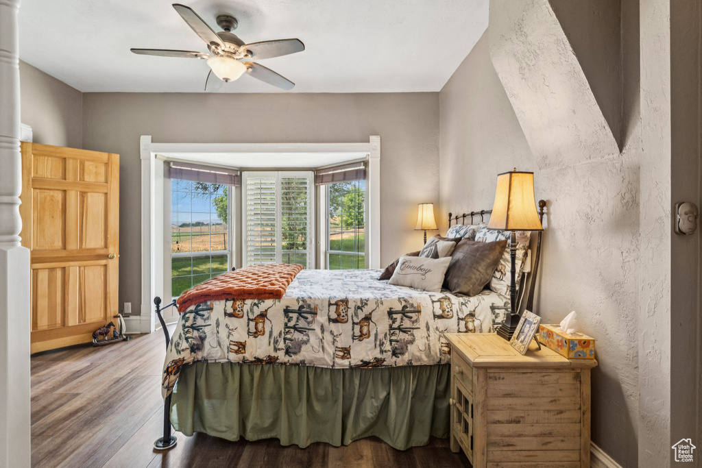 Bedroom with wood finished floors, ceiling fan, and a textured wall