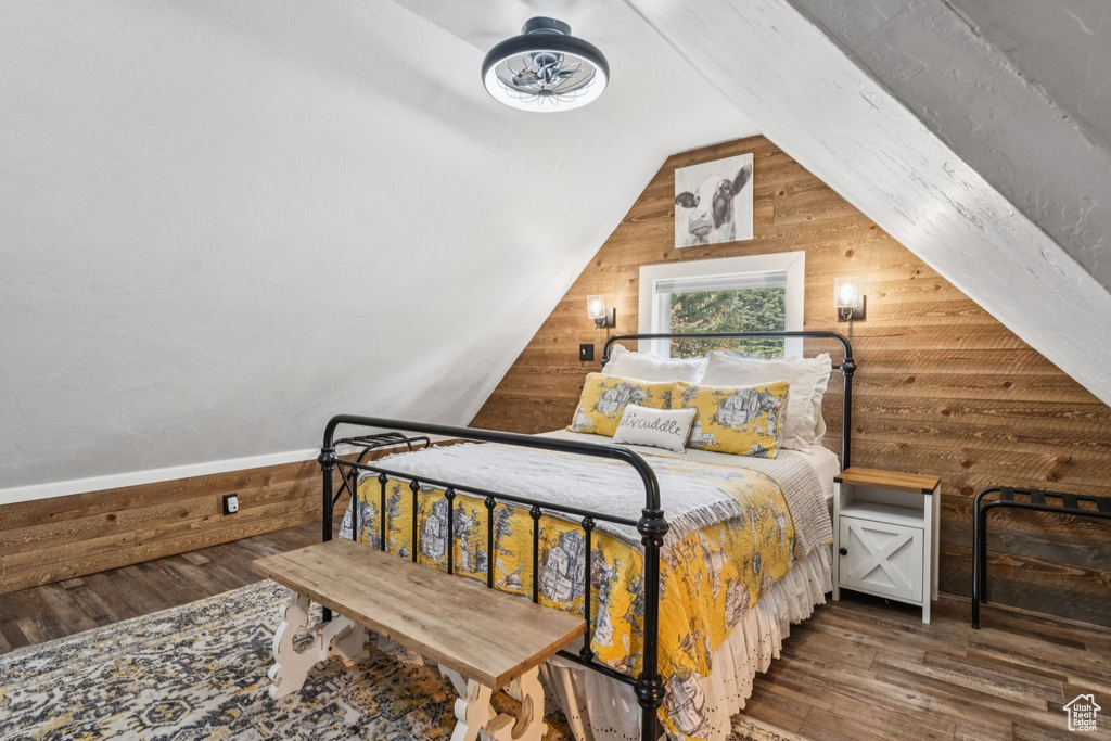 Bedroom with wood walls, wood finished floors, and vaulted ceiling
